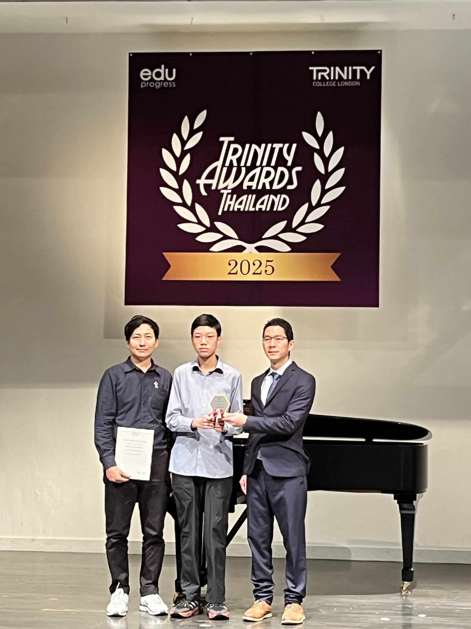 พิธีมอบรางวัล Trinity Awards Thailand 2025 บนเวที น้องริวนักเรียน NUS Music รับโล่รางวัล Acoustic Guitar Grade Initial คะแนน 95 อันดับ 3 ประเทศไทย จาก Trinity College London