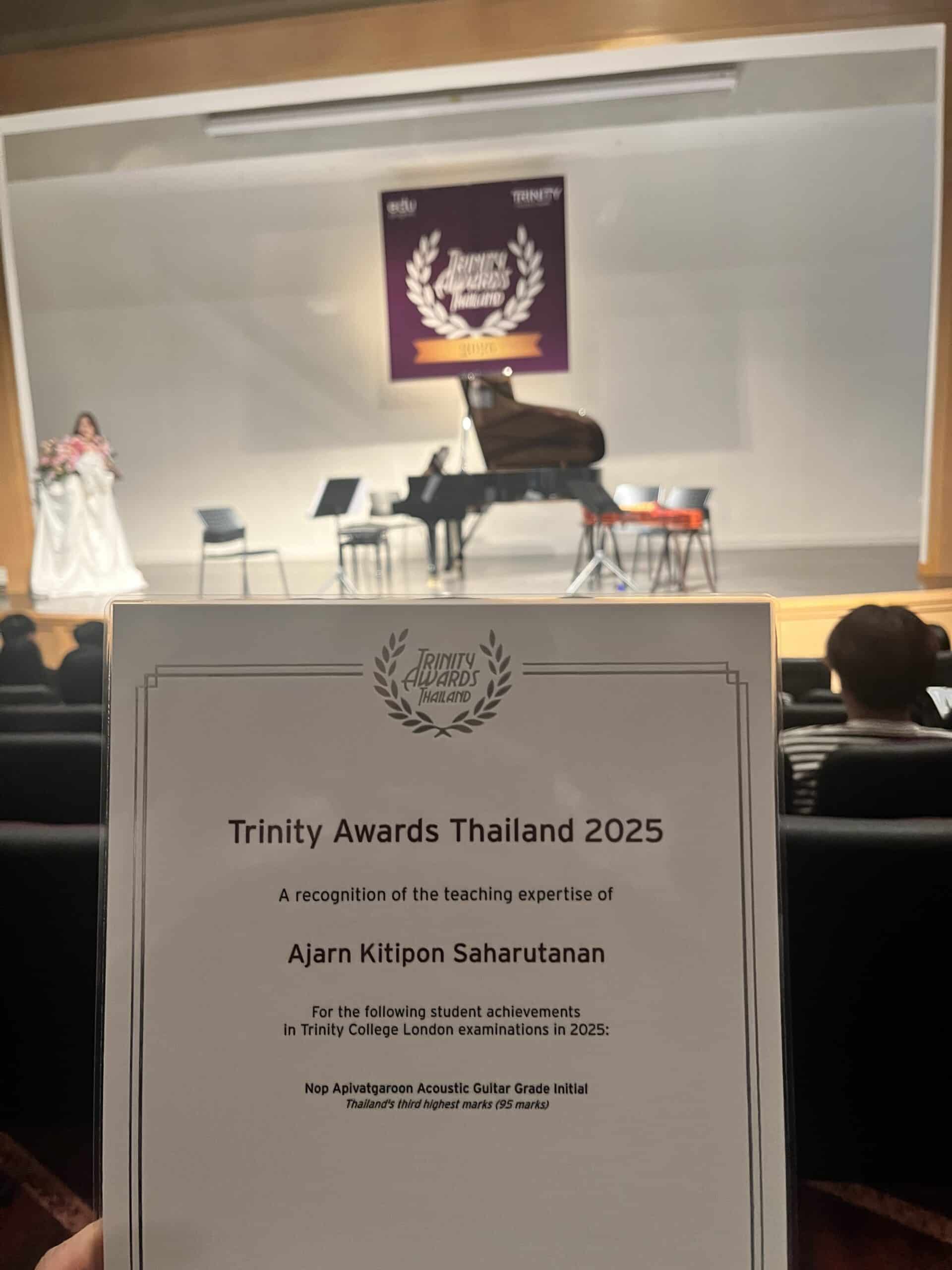 พิธีมอบรางวัล Trinity Awards Thailand 2025 บนเวที น้องริวนักเรียน NUS Music รับโล่รางวัล Acoustic Guitar Grade Initial คะแนน 95 อันดับ 3 ประเทศไทย จาก Trinity College London